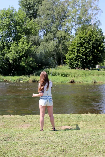 Jonge vrouw met zomer spruiten en werkbroeken tijdens het vissen — Stockfoto