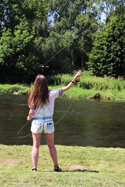 Ung kvinna med sommaren groddar och överdragskläder medan fisket — Stockfoto