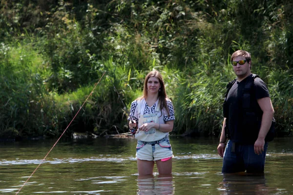 Jonge vrouw met zomer spruiten en werkbroeken tijdens het vissen — Stockfoto