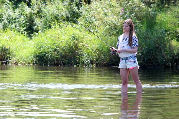 Jonge vrouw met zomer spruiten en werkbroeken tijdens het vissen — Stockfoto