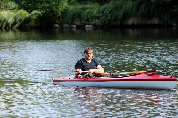 Jovem no caiaque vermelho enquanto pesca — Fotografia de Stock