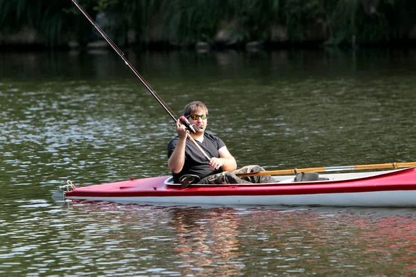 Jeune homme dans le kayak rouge tout en pêchant — Photo