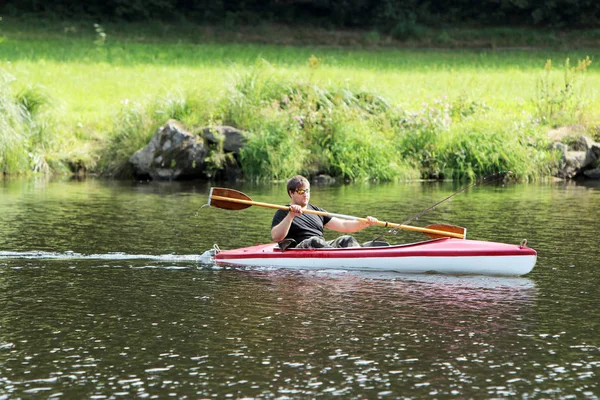 Jeune homme dans le kayak rouge tout en pêchant — Photo