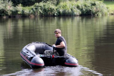Young man in inflatable boat with electric outboard