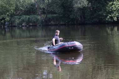 Young man in inflatable boat with electric outboard