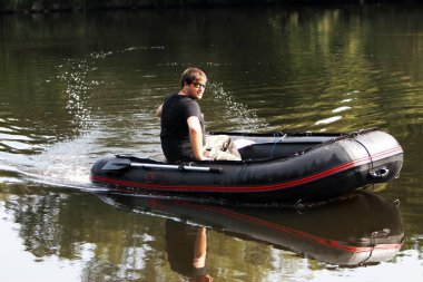 Young man in inflatable boat with electric outboard