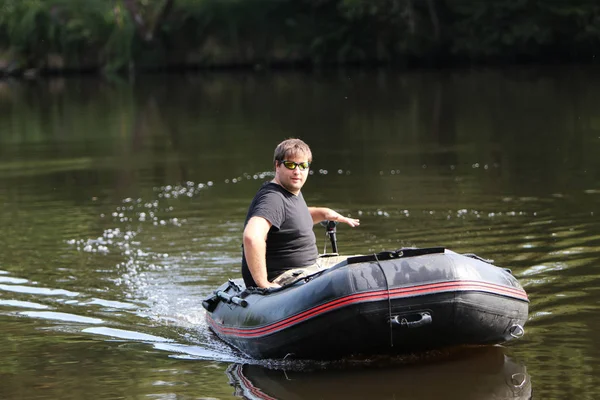 Jovem em barco inflável com popa elétrica — Fotografia de Stock