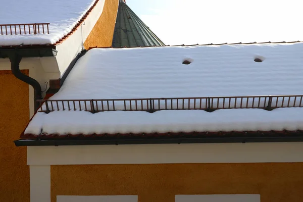 Snow covered roofs with snow guards Hiking trail in the snowy Bavarian countryside