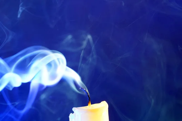 Yellow candle with smoke and flame photographed in the studio with color foils before the flashes