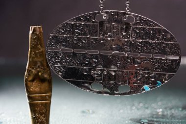 Stüdyoda su damlaları ve boş cephane kapsülleri olan künye.