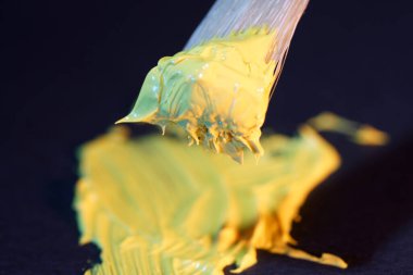 Sarı yeşil boya, siyah arka planda fırçası olan sanatçılar için tüpten yeni çekilmiş.                          