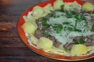 Besthe Ulusal Kazak yemeği - haşlanmış et, soğan ve ahşap bir masada kişniş ile yumurtalı erişte