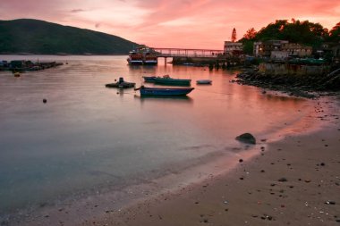 Sahil, tekneler ve gemi limanı ile günbatımı