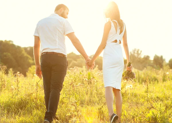 Pareja joven enamorada caminando en el parque de otoño tomados de la mano lo — Foto de Stock