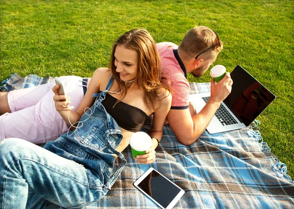 Paar verliefd zittend op het gras op vakantie in de buurt van de computer — Stockfoto