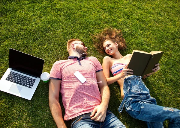 Iki bilgisayarın yakınına tatilde çimlerde oturan aşk içinde — Stok fotoğraf