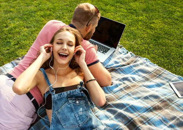 Couple in love sitting on the grass on holiday near the computer — Stock Photo, Image