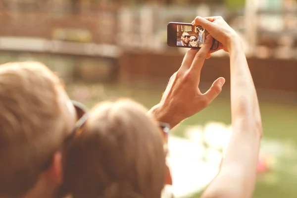 Par i kärlek sitter i parken vid solnedgången gör selfie — Stockfoto