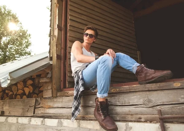 Μόδα hipster τύπος που κάθεται κοντά στον ξύλινο τοίχο — Φωτογραφία Αρχείου