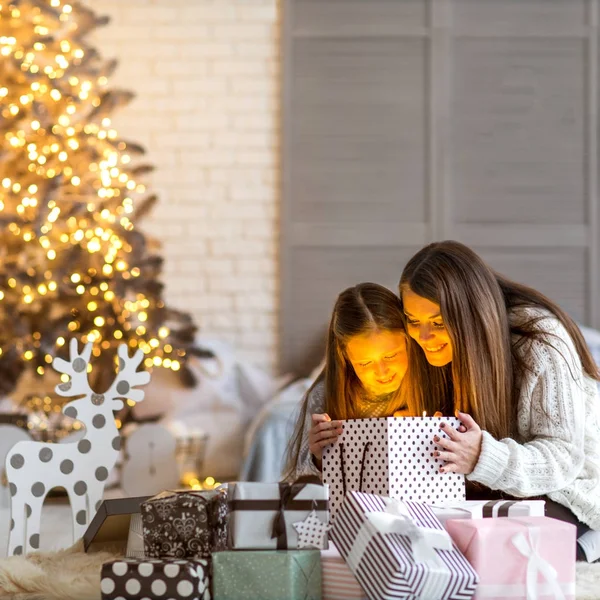 Молодая мать и ее маленькие дочери открывают волшебное Рождество — стоковое фото