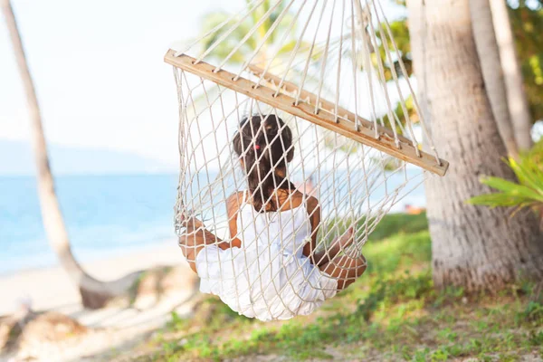 Ragazza felice sdraiata su un'amaca sulla riva di una spiaggia tropicale . — Foto Stock