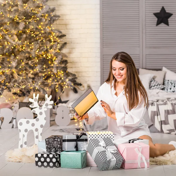 Mädchen an Weihnachten zu Hause beim Betrachten von Geschenken unter einem Weihnachtsbaum — Stockfoto