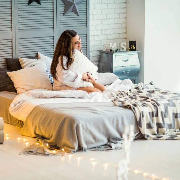 Dziewczyna, w domu na Boże Narodzenie przytulne siedział na łóżku w interio — Zdjęcie stockowe