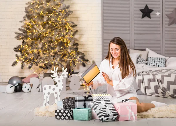 Mädchen an Weihnachten zu Hause beim Betrachten von Geschenken unter einem Weihnachtsbaum — Stockfoto