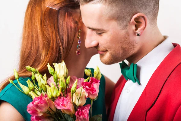 Hipster par i kärlek med en bukett blommor i studio ett — Stockfoto