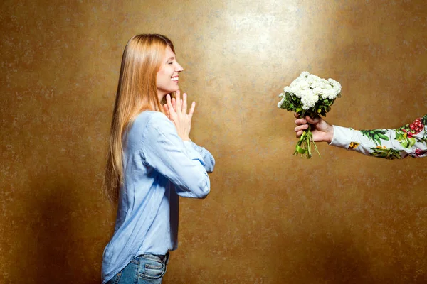 Девушка дарит цветы в студии на золотом фоне, conc — стоковое фото