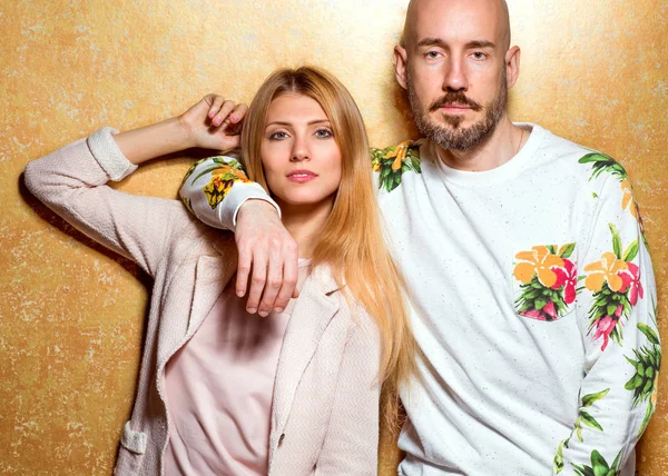 Chico de moda con una chica en el estudio posando sobre un fondo de oro — Foto de Stock