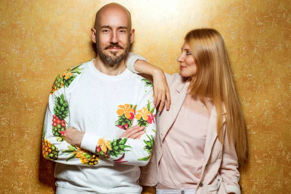 Mode kerel met een meisje in de studio poseren op een gouden pagina — Stockfoto