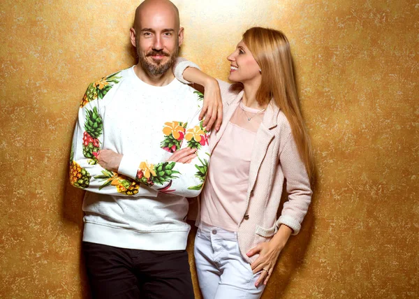 Mode killen med en tjej i studion poserar på en guld bak — Stockfoto
