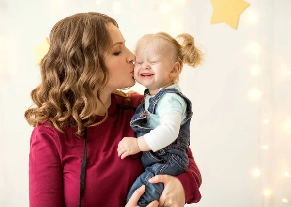 Mom with daughter on her arms emotionally hugs her at home — Stock Photo, Image