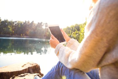 Kız bir göl sonbahar bir Parkı bir tablet tutar