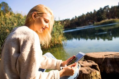 Kız bir göl sonbahar bir Parkı bir tablet tutar