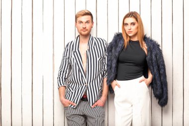 Sevgililer Günü'nde beyaz bir arka plan üzerinde moda çift. Moda alışveriş, mutlu bir şekilde gülümseyerek ve şaşırttı. Çizgili kıyafetler giymiş. Vogue stili