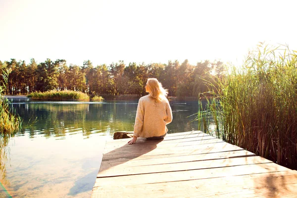 Menina em um parque de outono perto de um lago detém um tablet — Fotografia de Stock