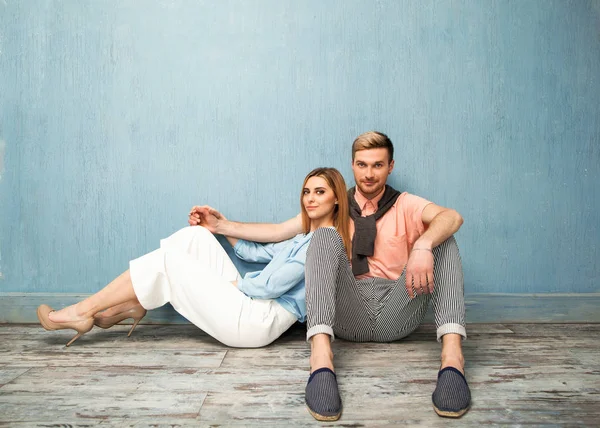 Fashion girl and guy in outlet clothes posing on a blue backgrou — Stock Photo, Image