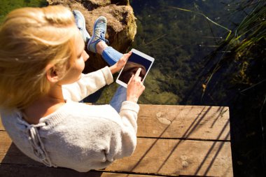 Kız bir göl sonbahar bir Parkı bir tablet tutar