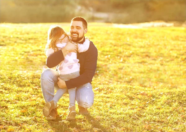 Fadern spelar med dotter i höst park vid solnedgången — Stockfoto