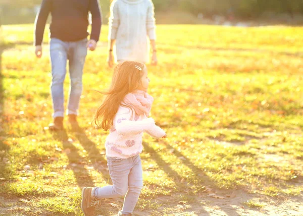 Pais brincando com a filha no parque ao pôr do sol — Fotografia de Stock