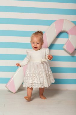 büyük bir şeker ile çizgili bir arka plan yakınındaki küçük kız duruyor