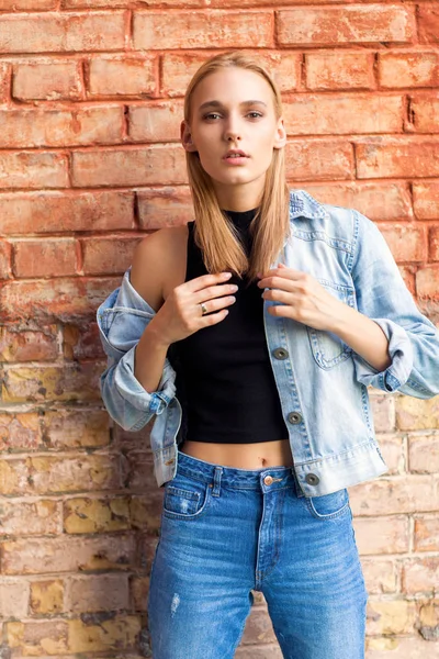 Fashion girl standing near brick wall in denim and sneakers. Vogue Style — Stock Photo, Image