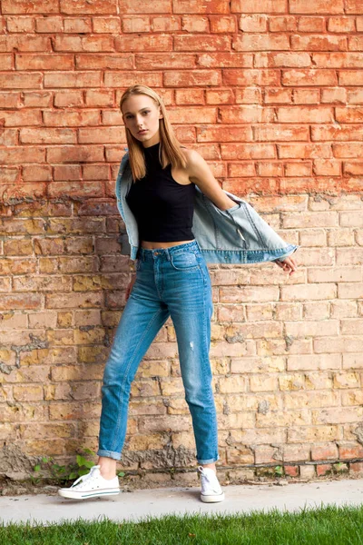 Móda dívka stojící u zdi v džínové a tenisky. Vogue styl — Stock fotografie