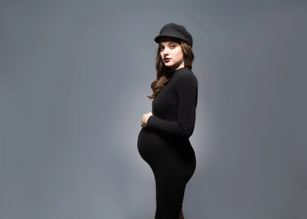 Красивая модная девушка беременная в студии стоит позируя — стоковое фото