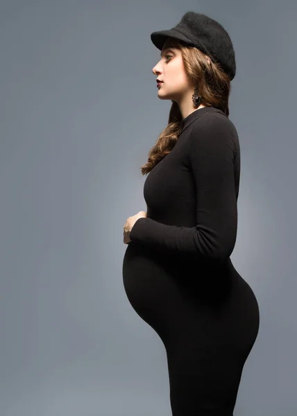 Красивая модная девушка беременная в студии стоит позируя — стоковое фото