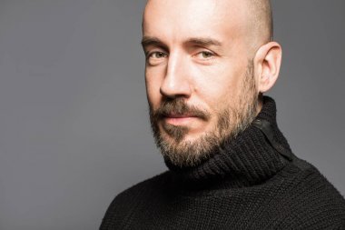 40 yaşındaki adam ayakta bir elma tutan bir siyah kazak moda portre. Yakın çekim. Klasik tarzı. Kel kafası tıraşlı. Boşluk. Stüdyo vurdu