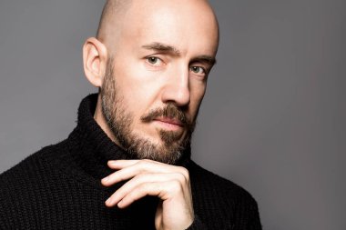 40 yaşındaki adam ayakta bir elma tutan bir siyah kazak moda portre. Yakın çekim. Klasik tarzı. Kel kafası tıraşlı. Boşluk. Stüdyo vurdu