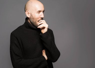 40 yaşındaki adam ayakta bir elma tutan bir siyah kazak moda portre. Yakın çekim. Klasik tarzı. Kel kafası tıraşlı. Boşluk. Stüdyo vurdu